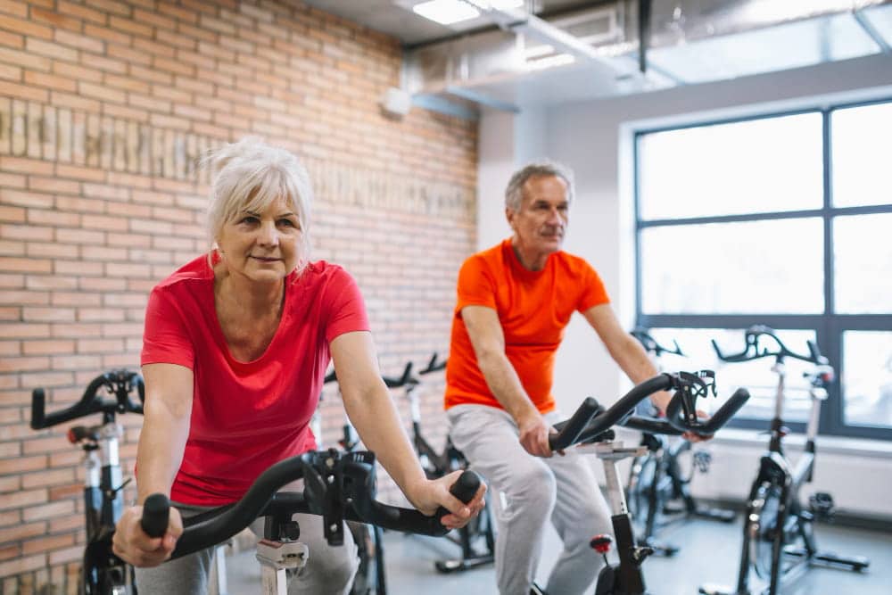 Programme vélo elliptique senior : un homme et une femme font du vélo elliptique