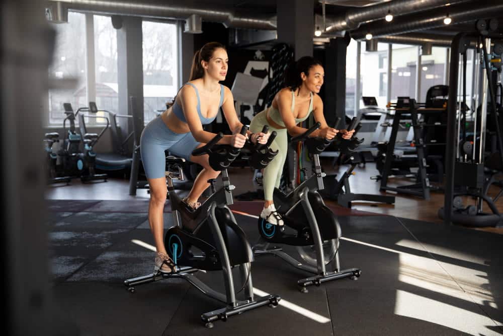 Recuperation active velo d'appartement : deux femmes font du vélo d'appartement