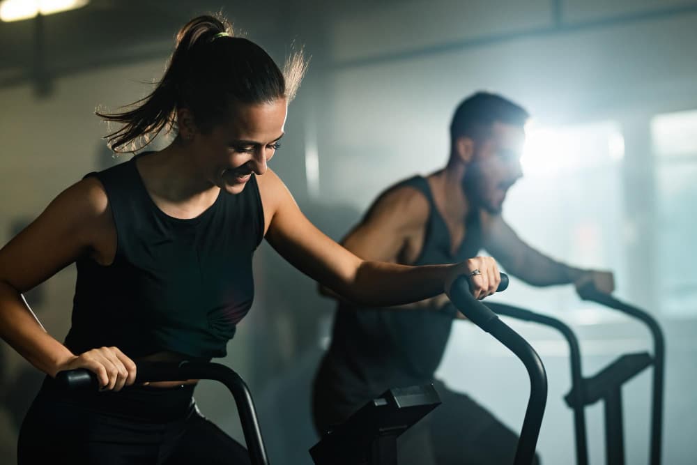 Programme hiit vélo stationnaire : un homme et une femme fait une séance de hiit sur un vélo