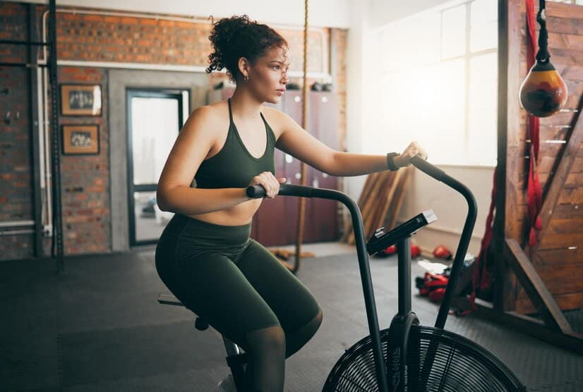 Programme hiit vélo stationnaire : une femme pratique du vélo stationnaire