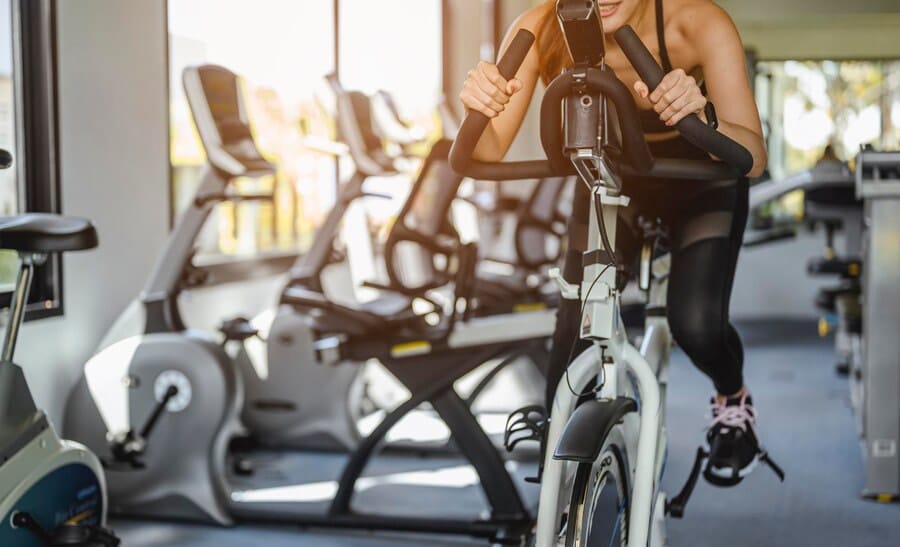 Comment améliorer son souffle en vélo : une femme fait du vélo d'appartement