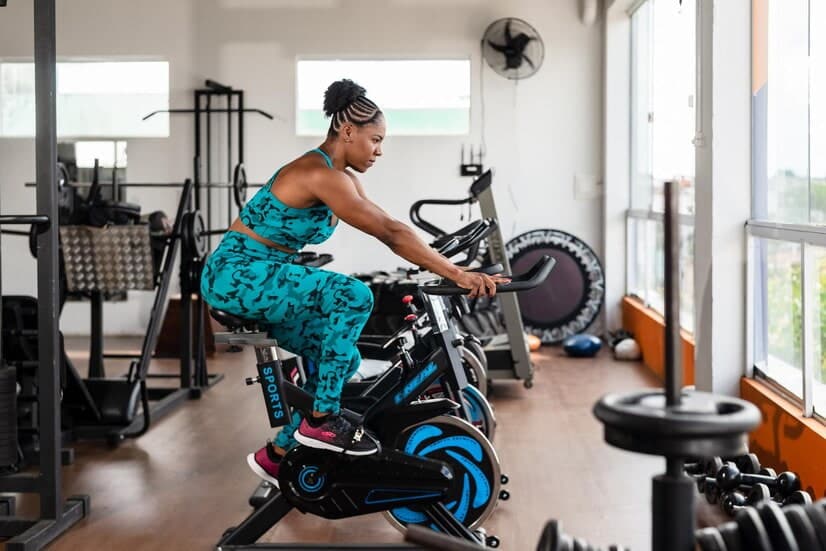 Comment améliorer son souffle en vélo : une femme fait du vélo d'appartement en salle