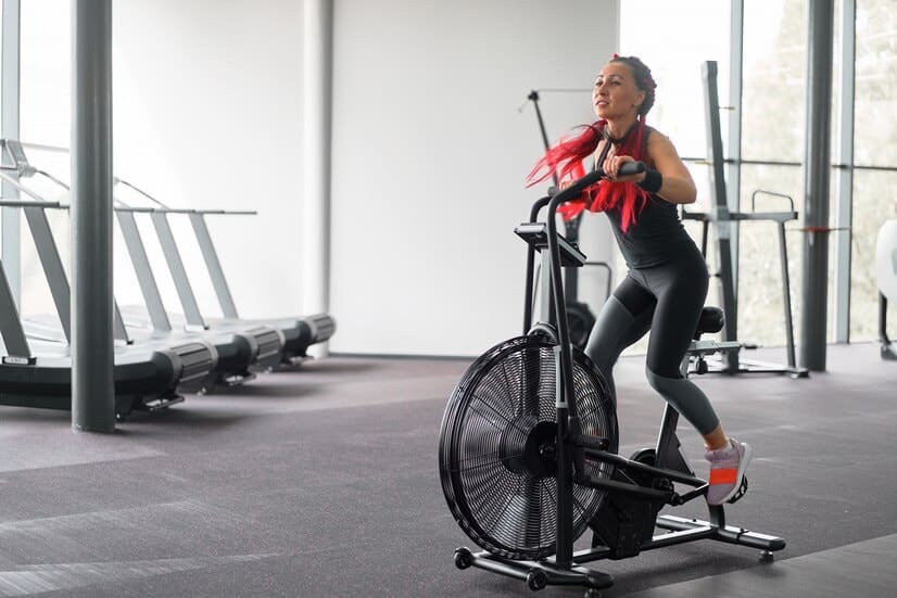 Mal de dos et velo d'appartement : Une femme fait du vélo d'appartement